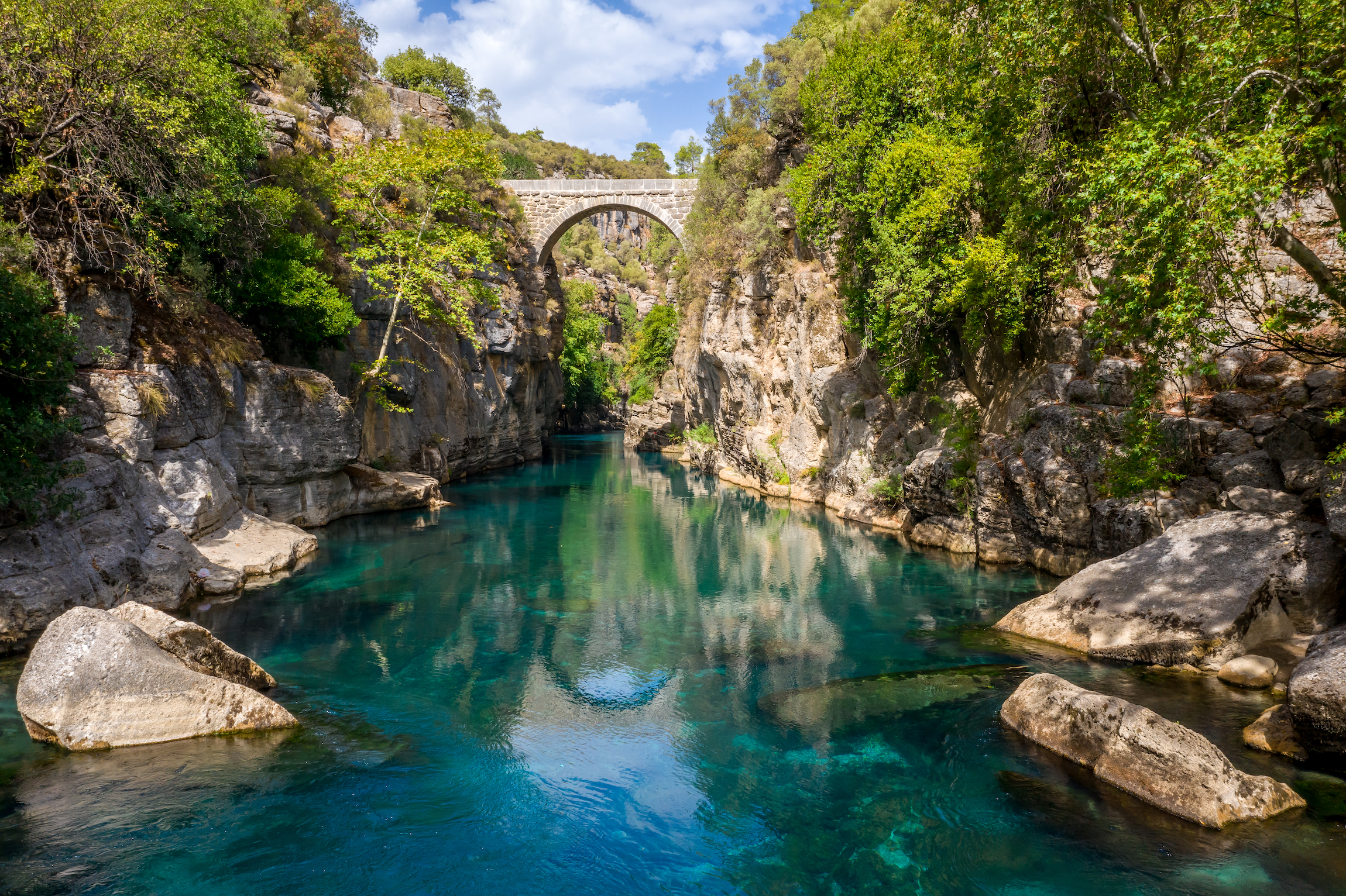 Starożytny most łukowy Oluk nad przełomem rzeki Koprucay w Parku Narodowym Koprulu w Turcji. Panoramiczny widok na kanion i niebieską burzliwą górską rzekę