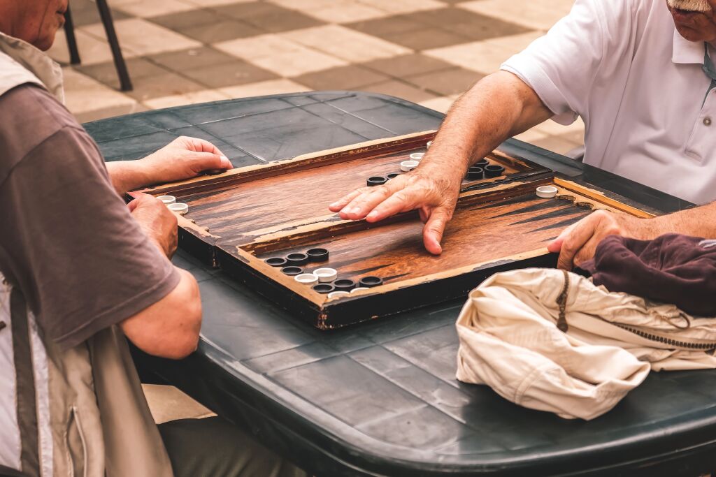 pamiątki - Gra planszowa backgammon. Dwóch starszych dorosłych mężczyzn grających w backgammon na ulicy, hobby