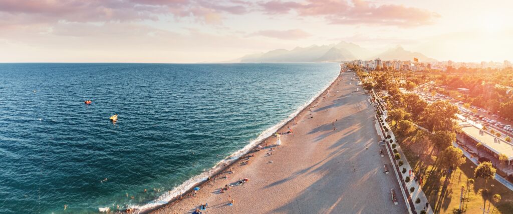 TOP 10 najpiękniejszych plaż - Widok z powietrza na malowniczą i popularną plażę Konyaalti w mieście wypoczynkowym Antalya. Majestatyczne góry z mgły w tle. Wakacje i urlop w Turkiye