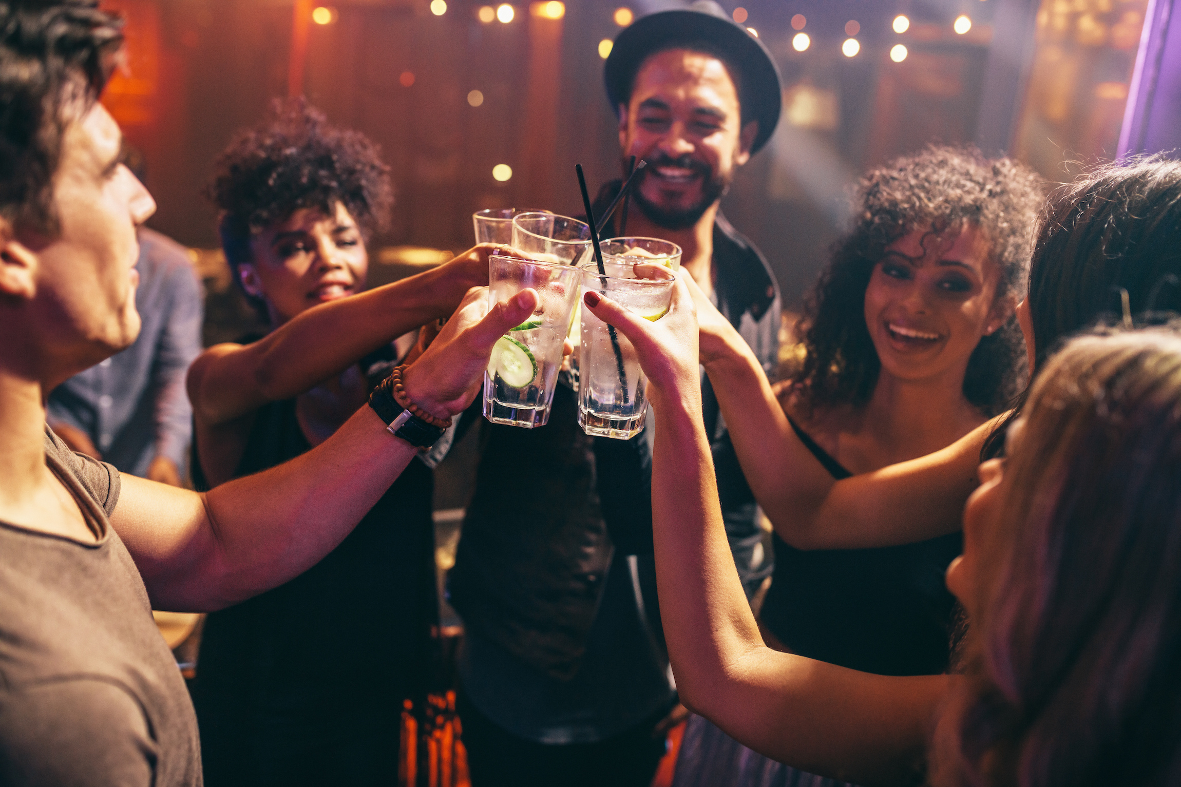 Grupa przyjaciół pijących drinki na imprezie w klubie nocnym. Młodzi ludzie cieszą się w barze opiekającym się koktajlami.
