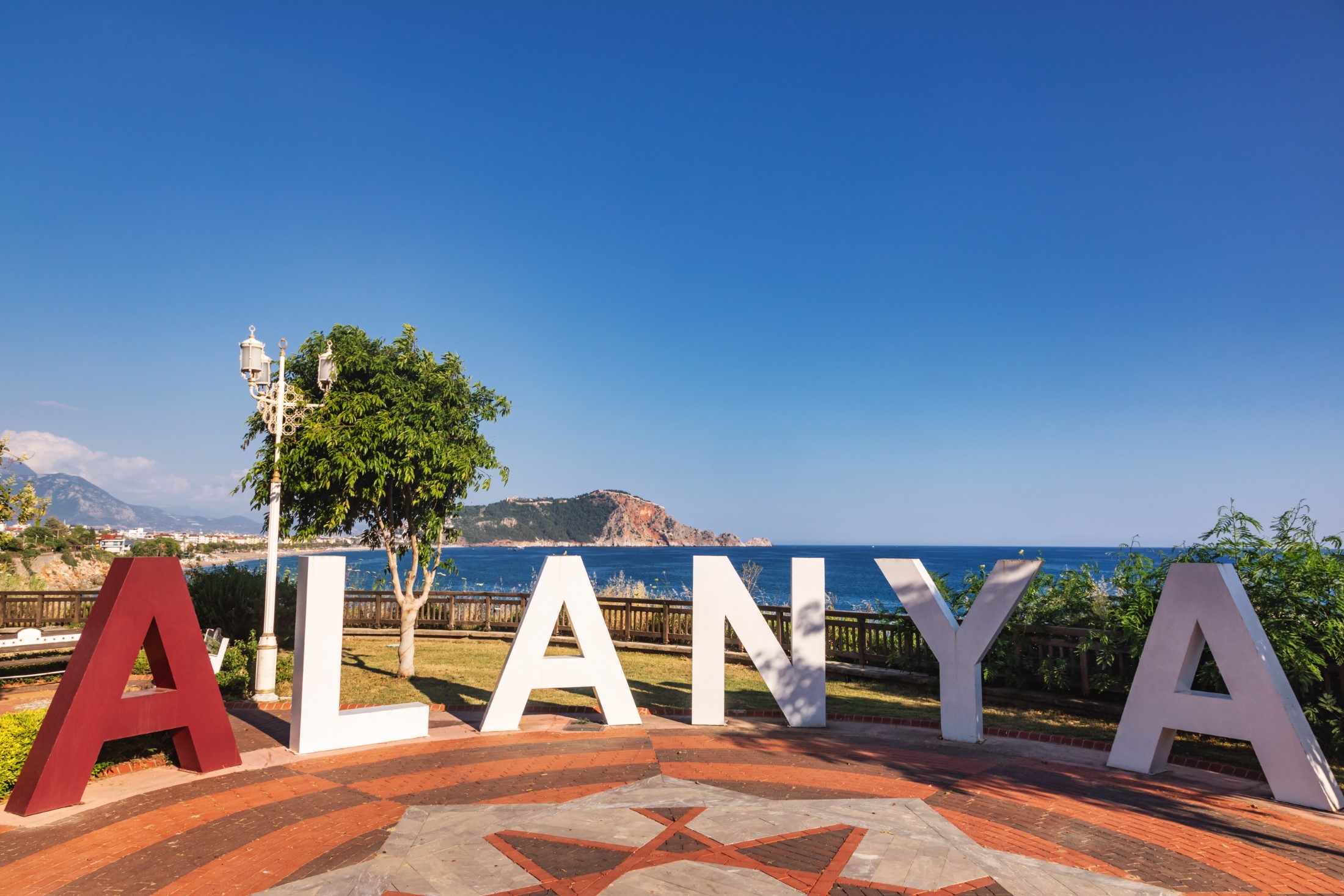 ALANYA sign with a scenic view of the sea and   Alanya Castle in the background